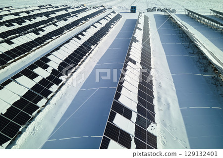 Aerial view of electrical power plant with solar panels covered with snow melting down in winter end for producing clean energy. Concept of low effectivity of renewable electricity in northern region Aerial view of electrical power plant with solar panels covered with snow melting down in winter end for producing clean energy. Concept of low effectivity of renewable electricity in northern region 129132401