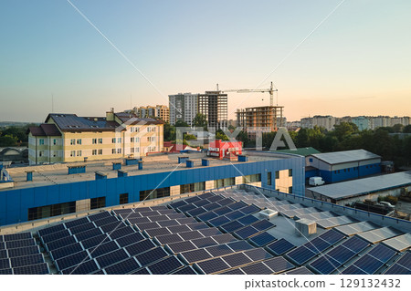 Aerial view of blue photovoltaic solar panels mounted on industrial building roof for producing green ecological electricity. Production of sustainable energy concept Aerial view of blue photovoltaic solar panels mounted on industrial building roof for producing green ecological electricity. Production of sustainable energy concept 129132432