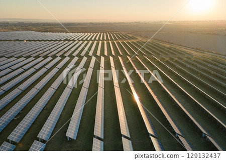 Aerial view of big sustainable electric power plant with many rows of solar photovoltaic panels for producing clean electrical energy at sunset. Renewable electricity with zero emission concept 129132437