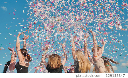 High school students celebrating graduation by throwing colorful confetti under a sunny blue sky High school students celebrating graduation by throwing colorful confetti under a sunny blue sky 129132847