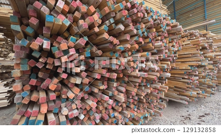 Colorful ends of square timber planks stacked in warehouse 129132858