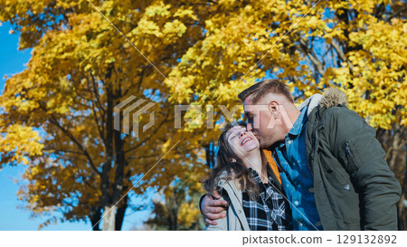 Loving father hugging, kissing young daughter amid golden autumn leaves in sunlit park with warm family connection Loving father hugging, kissing young daughter amid golden autumn leaves in sunlit park with warm family connection 129132892