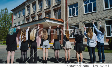 Happy students waving goodbye to high school on their last day, celebrating the end of the academic year Happy students waving goodbye to high school on their last day, celebrating the end of the academic year 129132941
