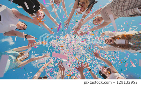 High school graduates joyfully tossing bright confetti in the air to celebrate their summer graduation 129132952