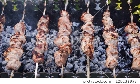 Beef meat is fried on skewers over an open fire. 129132955