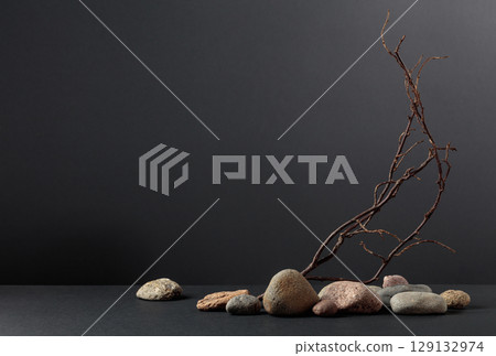 An intricately entwined branches and smooth stones against a black background. 129132974