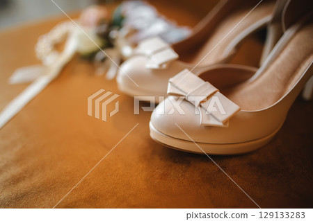 Wedding accessory bride. Stylish beige shoes, buttonhole and garter on wooden background. Wedding accessory bride. Stylish beige shoes, buttonhole and garter on wooden background. 129133283