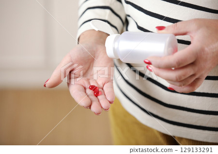 Close up 50 year old woman pouring out bottle pills time to take medication, treat memory loss, high blood pressure or cholesterol levels, pain medications, senile disease treatment concept 129133291