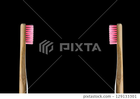 Eco friendly product concept. Zero waste two bamboo toothbrushes with pink bristle isolated on black background. Biodegradable material. Natural organic wooden brushes. Safe the earth. Copy space Eco friendly product concept. Zero waste two bamboo toothbrushes with pink bristle isolated on black background. Biodegradable material. Natural organic wooden brushes. Safe the earth. Copy space 129133301
