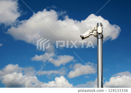 Outdoor security cctv cameras on a pole with blue cloudy sky background 129133336