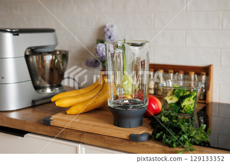 Healthy ingredients for detox smoothie drink and lifestyle diet. Glass blender bowl, apple, banana, broccoli, parsley on table top at modern home kitchen. Fresh fruits, vegetables and greens Healthy ingredients for detox smoothie drink and lifestyle diet. Glass blender bowl, apple, banana, broccoli, parsley on table top at modern home kitchen. Fresh fruits, vegetables and greens 129133352