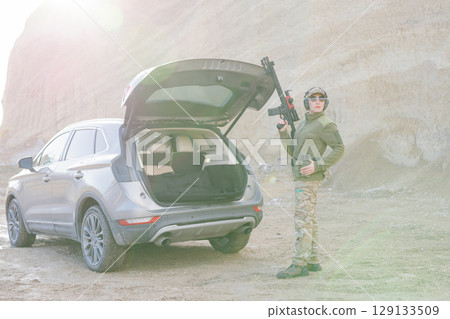 Female Soldier Holding Shotgun near Car with Open Trunk in Desert Area Female Soldier Holding Shotgun near Car with Open Trunk in Desert Area 129133509