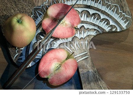 Fresh kissabel apple fruit and Cut the apple in each half with knife on wooden cutting board. Fresh kissabel apple fruit and Cut the apple in each half with knife on wooden cutting board. 129133750