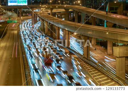 A night view with bright glowing light trails effect of many cars headlights and rear lights on urban expressway. A night view with bright glowing light trails effect of many cars headlights and rear lights on urban expressway. 129133773