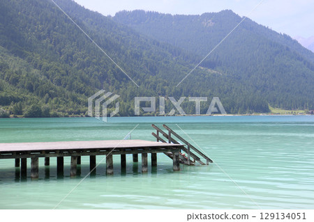 Wooden pier on turquoise Achensee lake in Tyrol, Austria - peaceful summer scene in the Alps 129134051