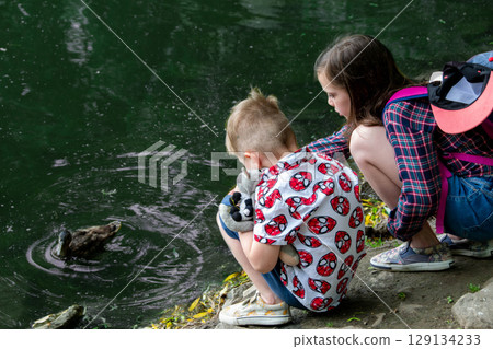 Small children playing on a pond handsome teenagers launches kite on the sea in blue sky, close up. High quality photo Small children playing on a pond handsome teenagers launches kite on the sea in blue sky, close up. High quality photo 129134233