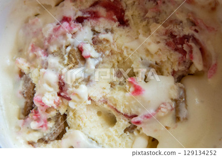 Close up of white and red ice cream, ice cream with strawberries jam and chocolate, macro, closeup. High quality photo 129134252