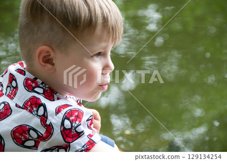 Small boy playing on a pond handsome teenager boy launches kite on the sea in blue sky, close up. High quality photo Small boy playing on a pond handsome teenager boy launches kite on the sea in blue sky, close up. High quality photo 129134254