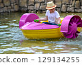 Kid playing rowing water paddle boat. Soft focus. A little girl rides a colorful boat on a pool in a resort. High quality photo 129134255
