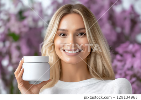 Portrait of a smiling well-groomed beautiful woman with a jar of moisturizer in her hands 129134963