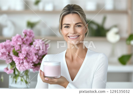 Portrait of a smiling well-groomed beautiful woman with a jar of moisturizer in her hands 129135032