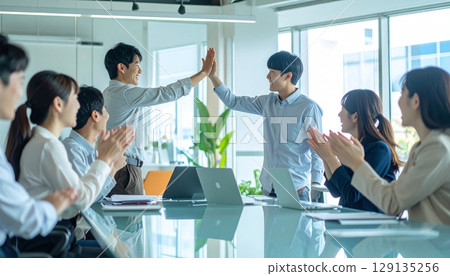 Business people high-fiving in a bright office 129135256