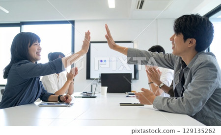 Business people high-fiving in a bright office Business people high-fiving in a bright office 129135262