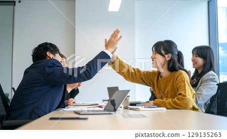 Business people high-fiving in a bright office Business people high-fiving in a bright office 129135263