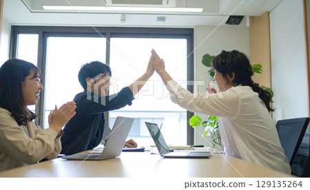 Business people high-fiving in a bright office Business people high-fiving in a bright office 129135264