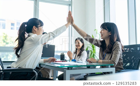 Business people high-fiving in a bright office Business people high-fiving in a bright office 129135283