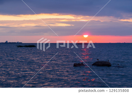 Scenic sunset over the sea. The sun is peeking out from behind the clouds. Scenic sunset over the sea. The sun is peeking out from behind the clouds. 129135808