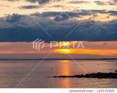 Scenic sunset at the beach. The sky is painted in bright colors. Dramatic cloudscape over the sea. Calm summer evening. Scenic sunset at the beach. The sky is painted in bright colors. Dramatic cloudscape over the sea. Calm summer evening. 129135809