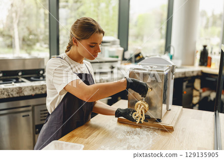 A Young Woman Diligently Preparing Delicious Pasta in Modern Contemporary Kitchen Style A Young Woman Diligently Preparing Delicious Pasta in Modern Contemporary Kitchen Style 129135905