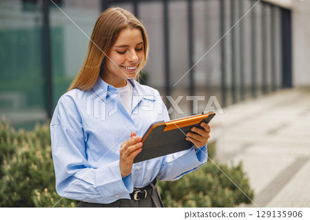 A Young Professional Engaged with a Tablet in an Outdoor Environment in a City Setting A Young Professional Engaged with a Tablet in an Outdoor Environment in a City Setting 129135906