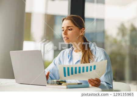 A Focused Professional Dedicatedly Analyzing Data on a Laptop at a Modern, Trendy Workspace 129135965