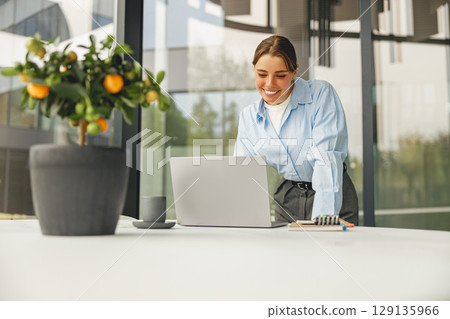A Skilled Professional Woman Engaged in Her Work Within a Contemporary Office Setting Using a Laptop A Skilled Professional Woman Engaged in Her Work Within a Contemporary Office Setting Using a Laptop 129135966