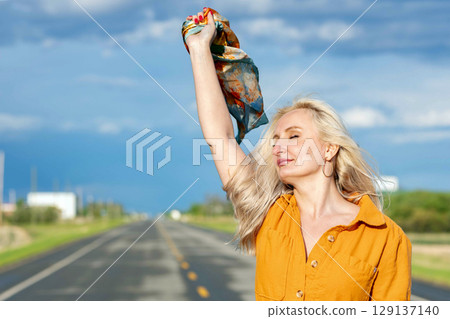 Blonde free woman is on the empty rural road in summer. Blonde free woman is on the empty rural road in summer. 129137140