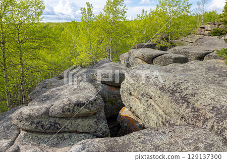 Ancient rock formation in a green forest, geological site. 129137300