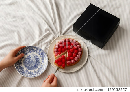 Delicious raspberry cake being served on a cozy bed with a stylish black box nearby Delicious raspberry cake being served on a cozy bed with a stylish black box nearby 129138257