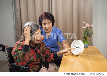 Asian Elderly Woman with Dementia Practicing Read Time on Clock. Asian Elderly Woman with Dementia Practicing Read Time on Clock. 129138557
