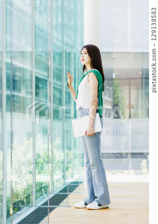 Smiling female college student with laptop in a university classroom 129138583
