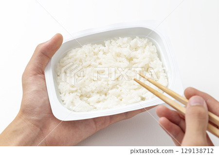Hands of a man eating packed rice Hands of a man eating packed rice 129138712