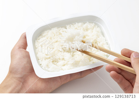 Hands of a man eating packed rice Hands of a man eating packed rice 129138713