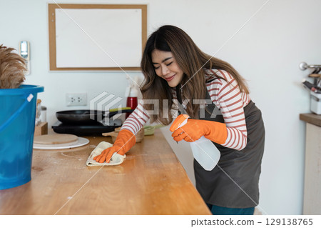 Professional Cleaning Service Worker Tidying Up a Modern Kitchen with Cleaning Supplies and Equipment for a Spotless Home Environment 129138765