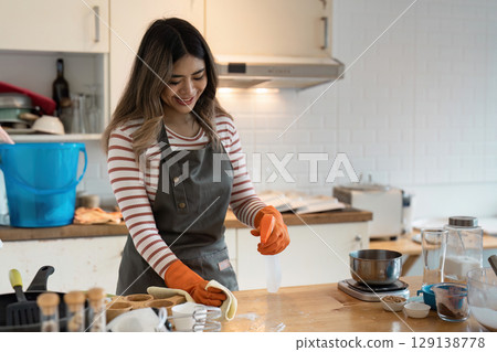 Professional Cleaning Service in Modern Kitchen with Smiling Worker Wearing Apron and Gloves for Home and Commercial Spaces 129138778