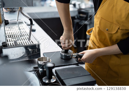 Barista Crafting Coffee in a Modern Small Business Startup Cafe Setting 129138830