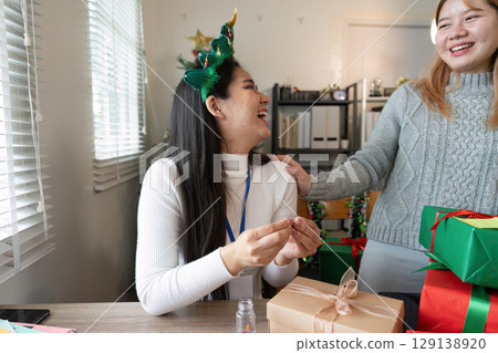 Festive Office Celebration with Colleagues Exchanging Gifts and Enjoying Holiday Spirit in a Modern Workspace Festive Office Celebration with Colleagues Exchanging Gifts and Enjoying Holiday Spirit in a Modern Workspace 129138920