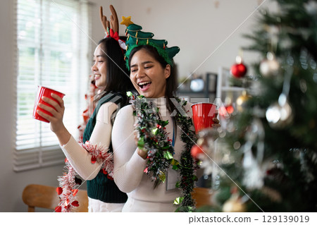 Festive Celebration with Friends Enjoying a Christmas Party in a Decorated Living Room with Holiday Cheer and Joyful Atmosphere 129139019