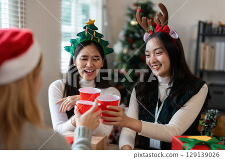 Festive Friends Celebrating Christmas with Joyful Toasts and Holiday Cheer in a Cozy Decorated Room Festive Friends Celebrating Christmas with Joyful Toasts and Holiday Cheer in a Cozy Decorated Room 129139026