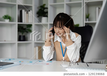 Stressed Office Worker Experiencing Office Syndrome at Desk with Computer and Documents in Modern Workplace Stressed Office Worker Experiencing Office Syndrome at Desk with Computer and Documents in Modern Workplace 129139068